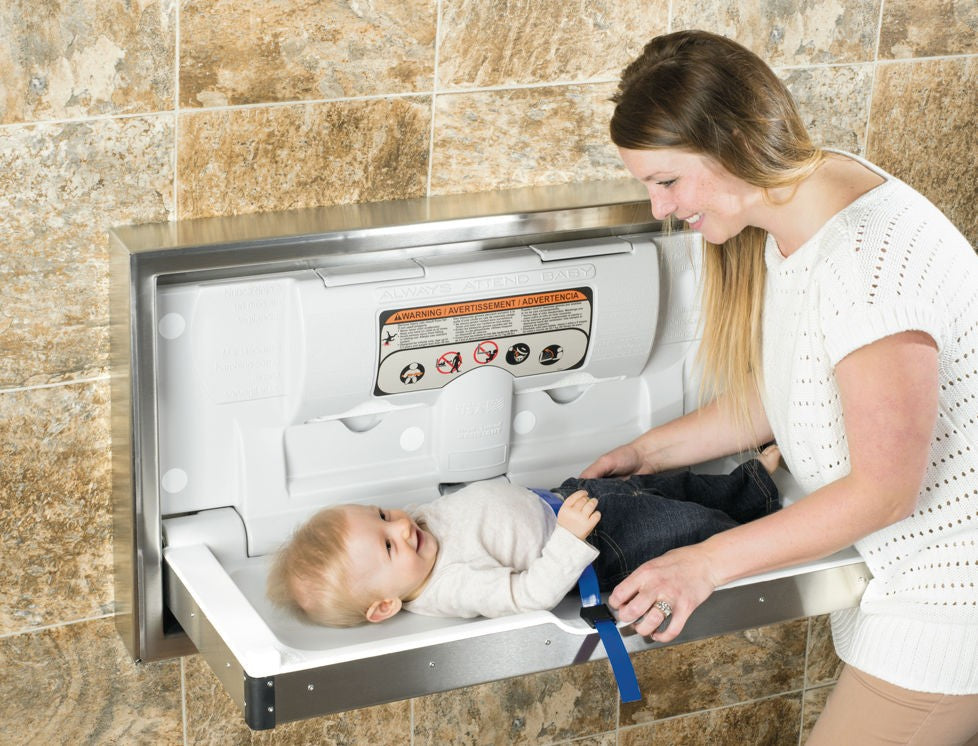 Parent changing a baby on the open Dolphy recessed baby change station in a tiled washroom