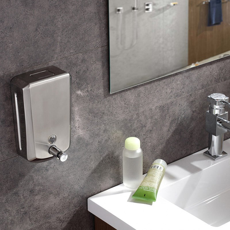 Dolphy stainless steel soap dispenser mounted on a grey tiled wall beside a basin
