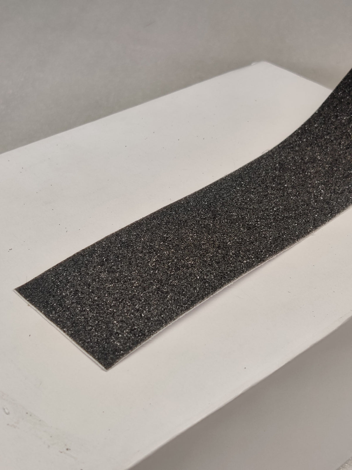 Close-up of the coarse grit surface of Dolphy black anti-slip tape applied to a step