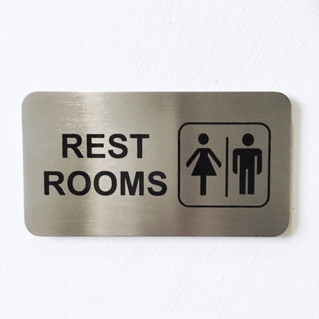 Stainless steel REST ROOMS sign with male and female symbols