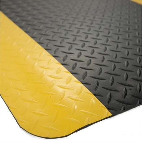 Close-up of the Dolphy anti-fatigue mat's black diamond-plate surface and yellow safety border