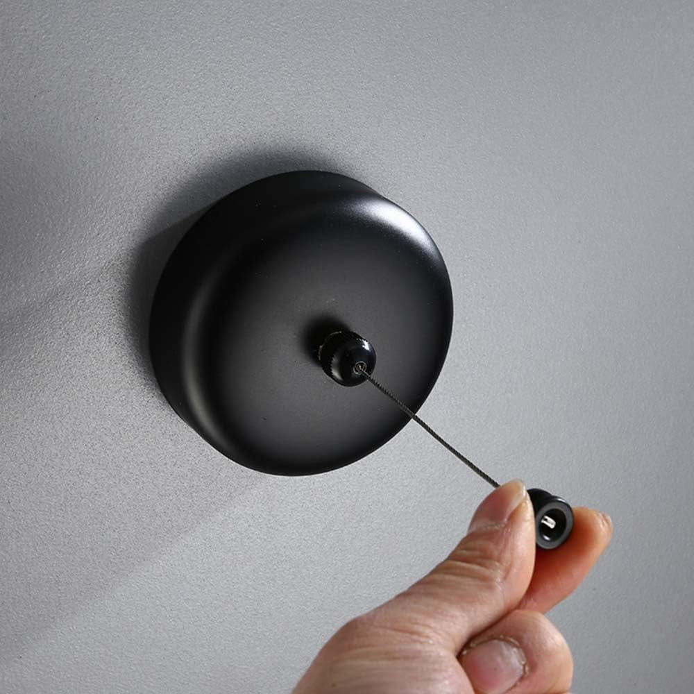 Hand pulling the line from the Dolphy black round retractable clothesline on a wall