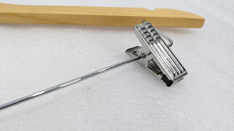 Close-up of the chrome trouser clip on the Dolphy natural wood security hanger