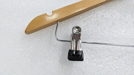 Close-up of a chrome trouser clip with rubber grip on the Dolphy wooden hanger