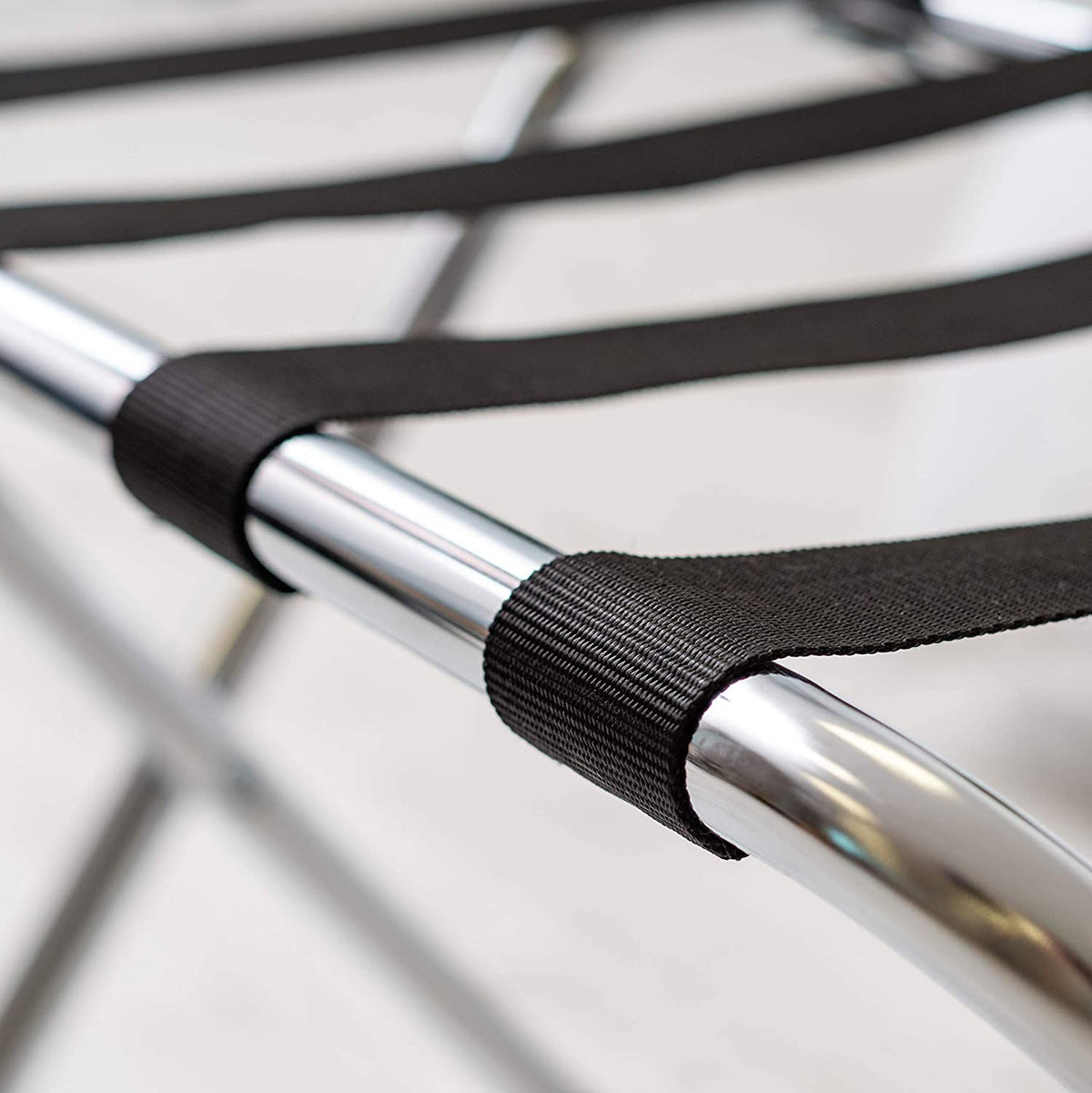 Close-up of the black nylon webbing straps looped over the Dolphy luggage rack's chrome frame