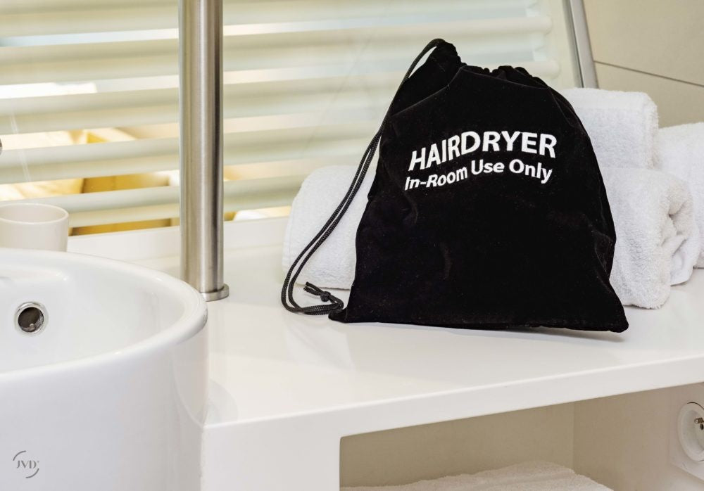 Dolphy black velvet HAIRDRYER In-Room Use Only bag on a hotel bathroom vanity