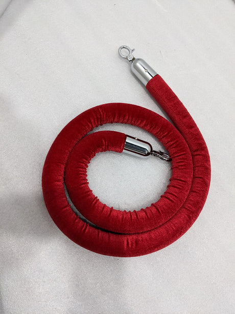 Dolphy red velvet barrier rope coiled, showing both chrome hook ends
