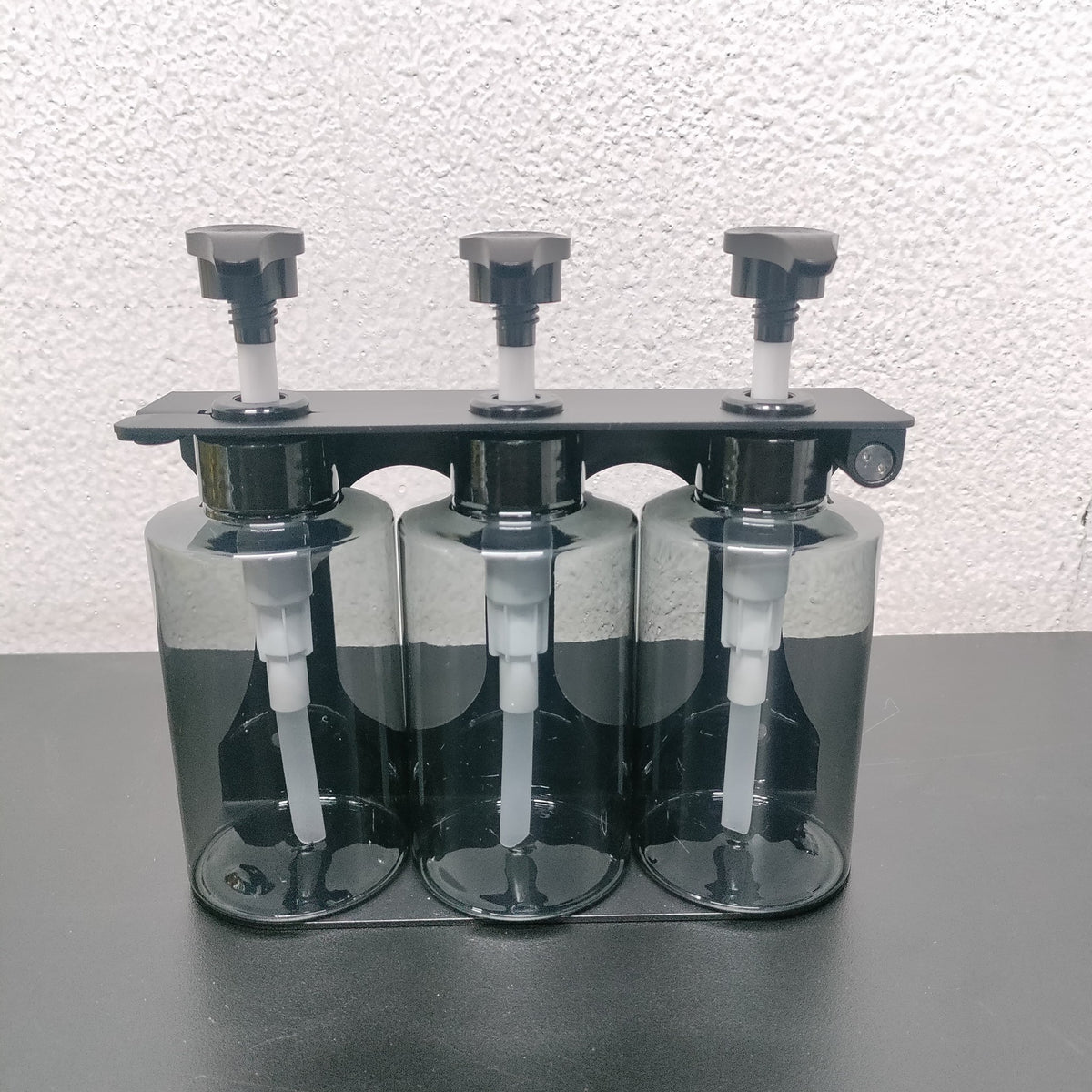 Dolphy triple dispenser with clear bottles showing the pump tubes, front view