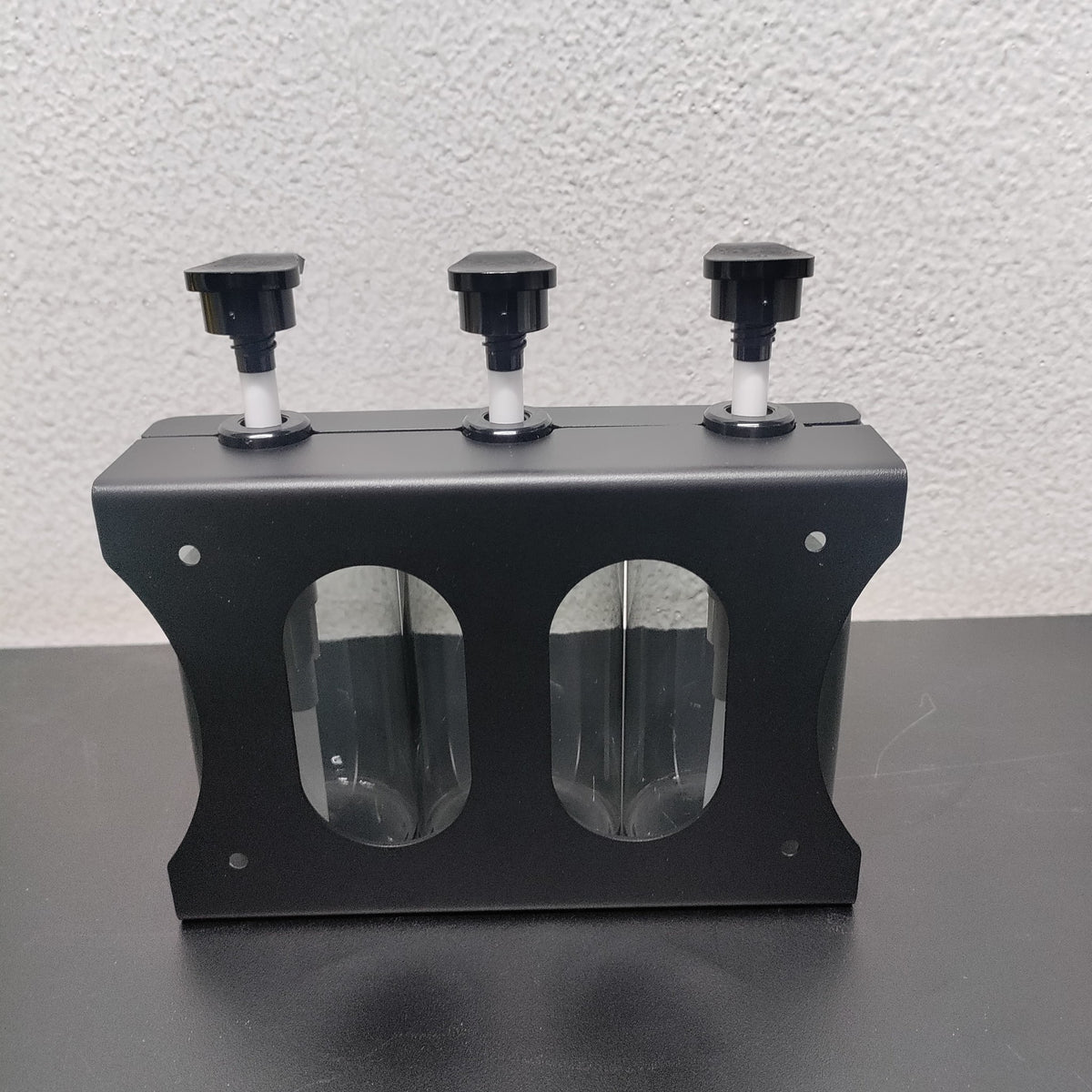 Back of the Dolphy triple dispenser's black steel wall bracket