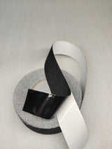 Dolphy black anti-skid tape with the white release liner peeled back from the adhesive