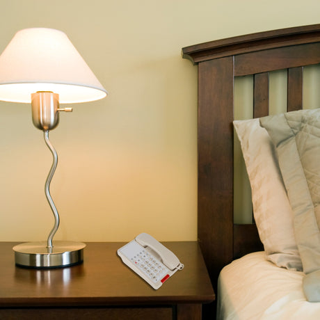 Dolphy beige telephone on a hotel bedside table beside a lamp