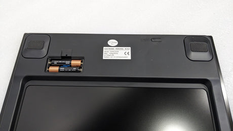 Underside of the Dolphy digital scale showing the battery compartment and non-slip feet